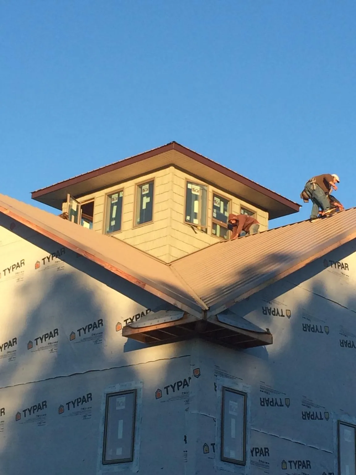 Roofers working around a rooftop cupola on a new metal roof at sunset — Roof Waterproofing in Jasper by Roofing Brothers